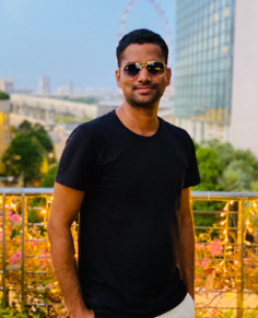 A person wearing sunglasses and standing in front of a railing  Description automatically generated