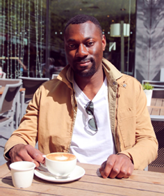 A person sitting at a table with a cup of coffee  Description automatically generated